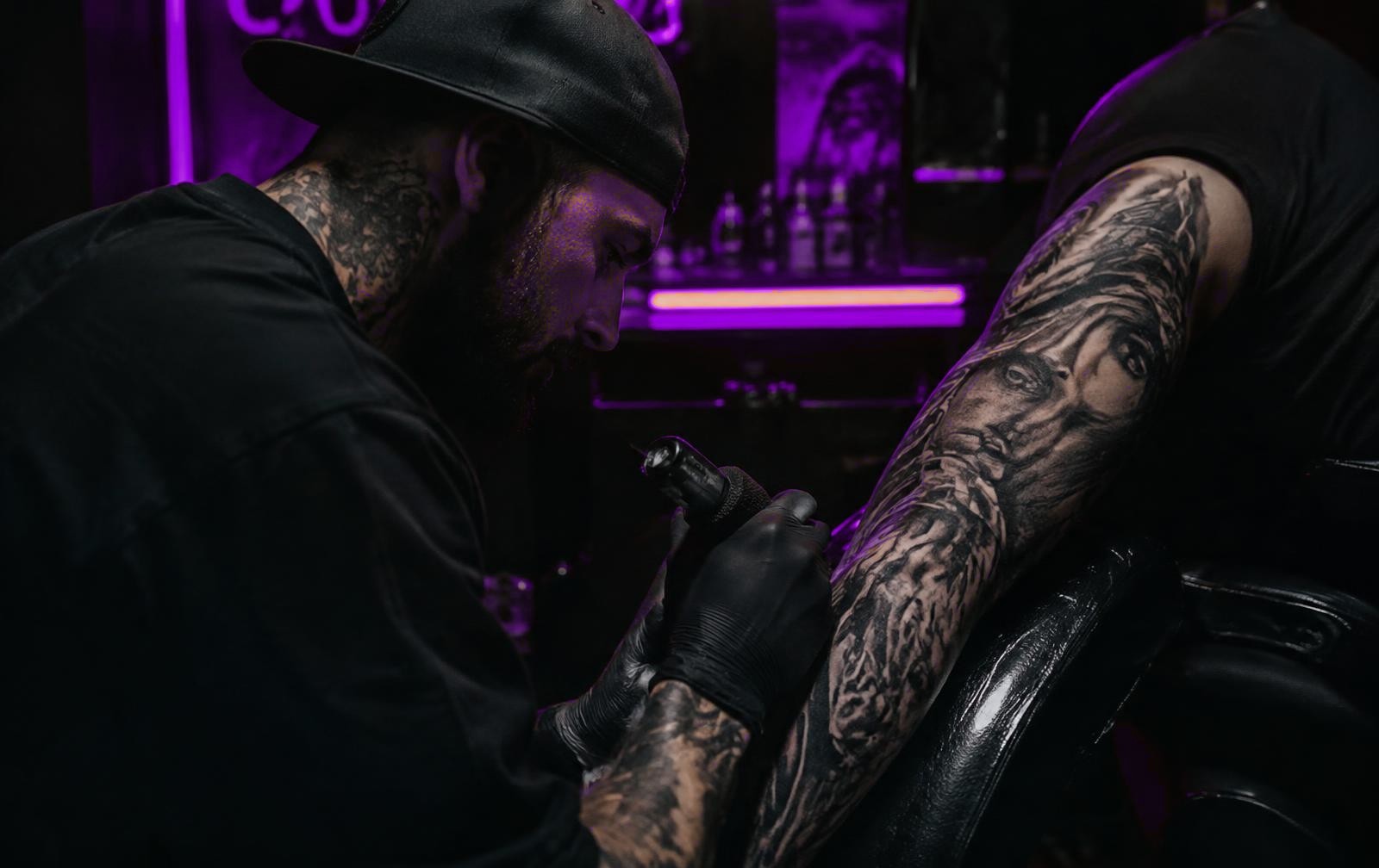 Artist tattooing a black and grey sleeve at Ink Lab